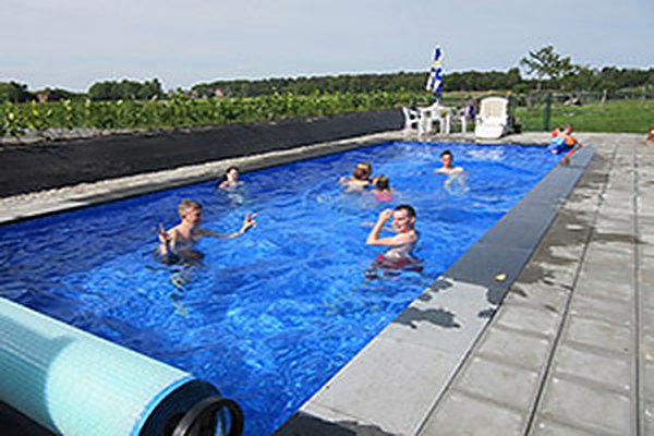Het omheinde zwembad van De Ossewei, met de camping en de velden erachter